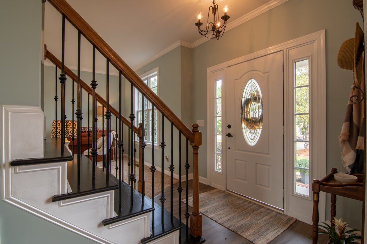 Inviting modern hallway with staircase, chandelier, and natural daylight.